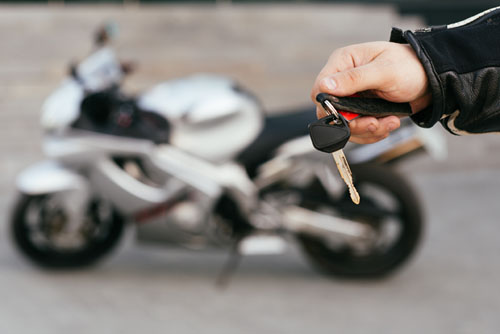 hands holding keys out by a new motorcycle